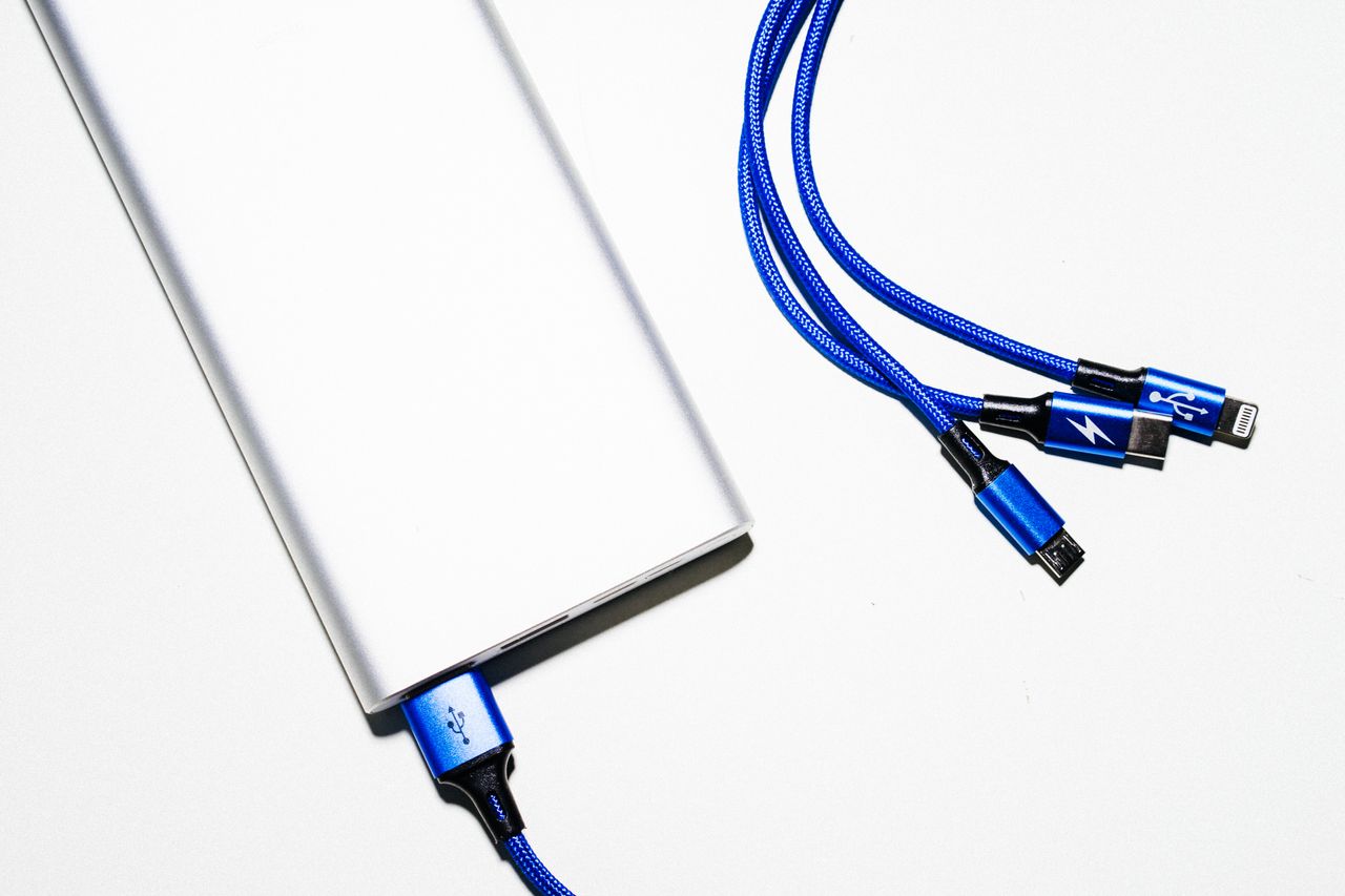 services-03 Minimalist image of a power bank with blue USB charging cables on a white background.